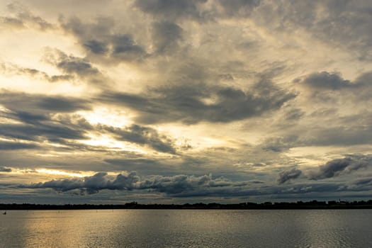 The clouds filled the sky, obscuring the light from the sun during the sunset. The sky on the top is coloured orange from the sun. The bottom sky is black and gray from the rain clouds.