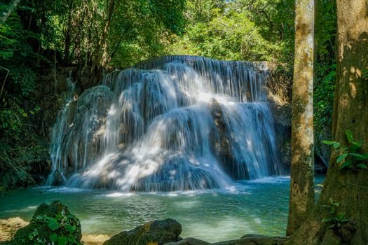 The clean waterfall there is an emerald green colour caused by reflections from trees and lichen circulating through the yellow limestone. Huai Mae Khamin Waterfall, Kanchanaburi Province