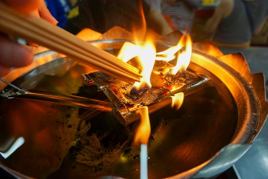 Incense is being lit by fire. From a large lamp