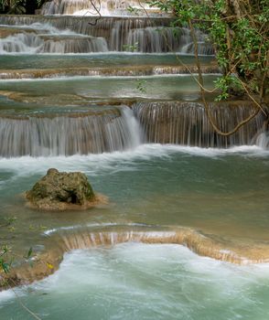 The clean waterfall there is an emerald green colour caused by reflections from trees and lichen circulating through the yellow limestone. Huai Mae Khamin Waterfall, Kanchanaburi Province