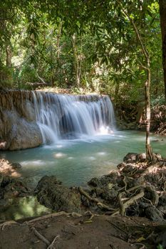 The clean waterfall there is an emerald green colour caused by reflections from trees and lichen circulating through the yellow limestone. Huai Mae Khamin Waterfall, Kanchanaburi Province