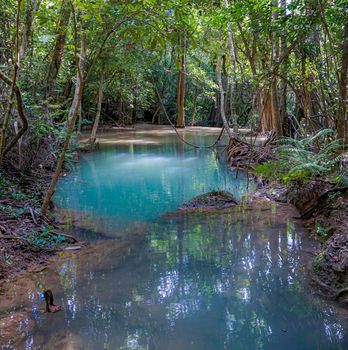 The clean waterfall there is an emerald green colour caused by reflections from trees and lichen circulating through the yellow limestone. Huai Mae Khamin Waterfall, Kanchanaburi Province