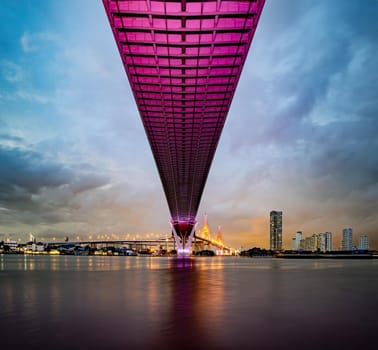 Purple led light under the bridge over the river On a cloudy day in the sky. Bhumibol Bridge, Samut Prakan, Thailand