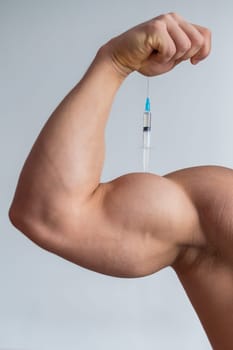 Close-up of male biceps. Unrecognizable male bodybuilder puts himself an injection of testosterone. Faceless athlete takes growth hormone. Vertical