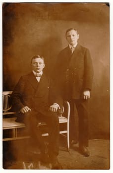 HAMBURG, GERMANY - CIRCA 1910s: Vintage photo shows young boys - brothers pose in a photography studio. Retro black and white photography with sepia effect. Circa 1910s.