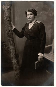 GERMANY - CIRCA 1920s: Vintage photo shows woman with short hair. Woman holds book. Retro black and white studio photography with sepia effect. Circa 1920s.