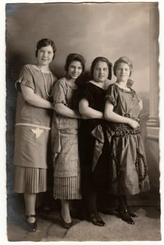 HAMBURG, GERMANY - CIRCA 1930s: Vintage photo shows a group of girls poses in the photography studio. Retro black and white photography with sepia effect. Circa 1930s.