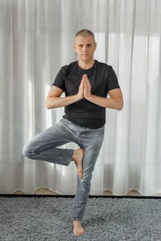 A man practicing yoga in the office on a break, exercise - Tree Pose.