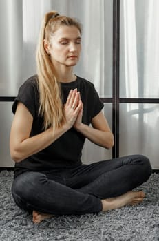 The concept of a healthy lifestyle. A woman meditates in the lotus position on a yoga mat during a break from work.