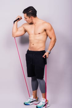 Athletic man skipping with jump rope on grey background. Best cardio workout