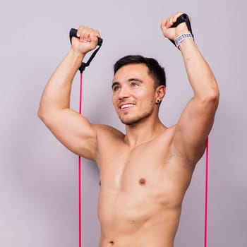 Athletic man skipping with jump rope on grey background. Best cardio workout