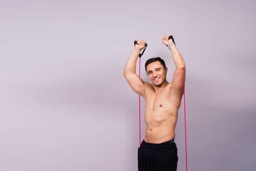 Athletic man skipping with jump rope on grey background. Best cardio workout