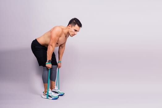 Athletic man skipping with jump rope on grey background. Best cardio workout