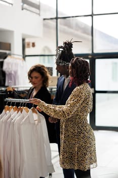 African american couple wanting to buy trendy shirt, asking showroom employee for help during commercial activity. Customers shopping for casual wear, buying fashionable clothes in modern boutique