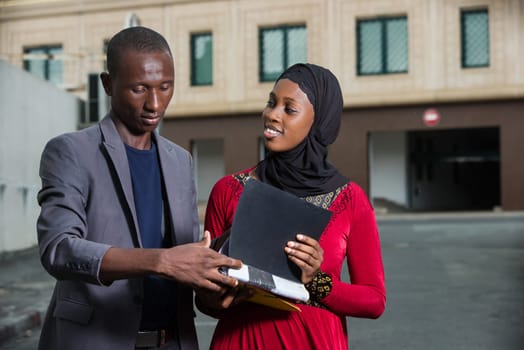 young businessman standing in the street checking his partner's folder while smiling.