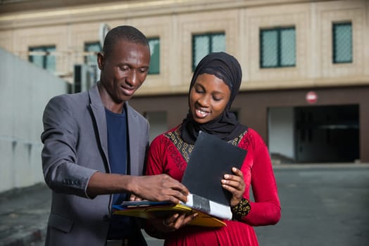 young businessman standing in the street checking his partner's folder while smiling.