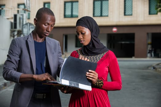 young businessman standing in the street checking his partner's folder.