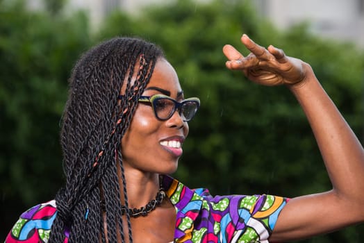young girl in glasses under a fine rain, looking in profile while smiling.