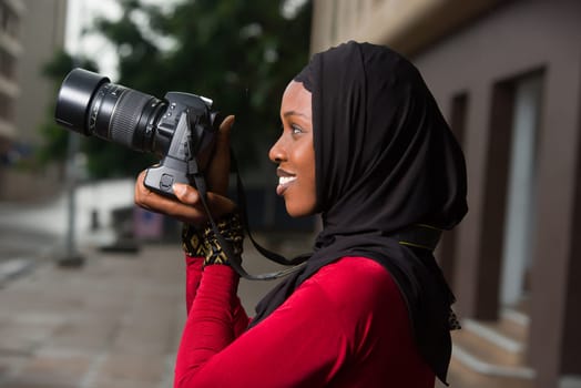 young muslim woman standing outdoors looking at camera smiling.