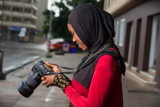 portrait of young muslim woman with camera, smiling.