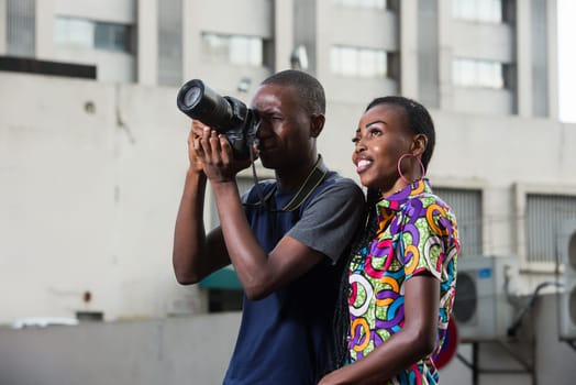young man standing in T-shirt photographing only assisted by his friend smiling.