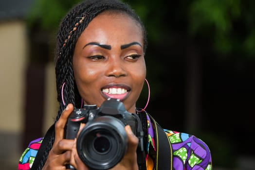 young woman standing right in camera looking at something smiling.