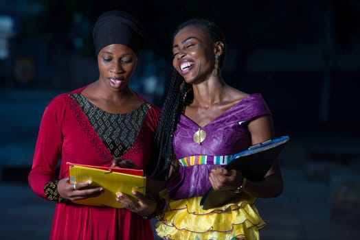 Young female students standing in the street after class talk talking with a smile.