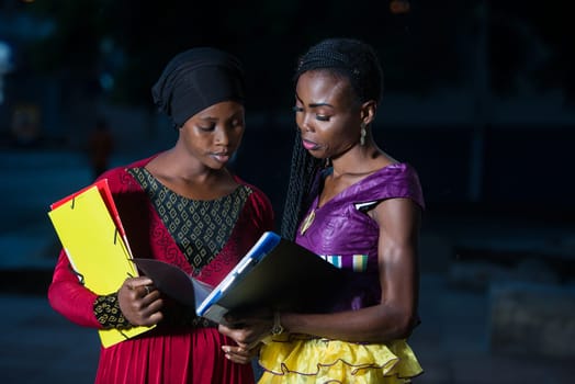 young female students standing in the street after classes go to check lesson.