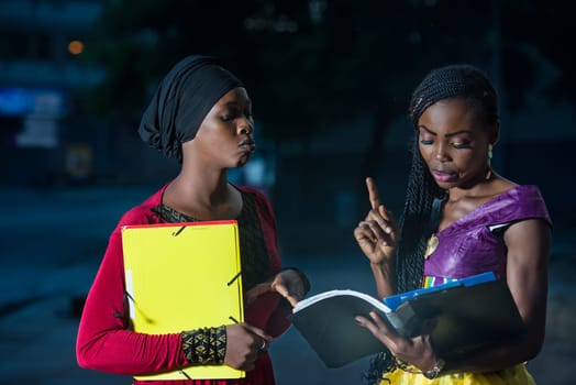 Young female students standing outdoors go checking lesson.