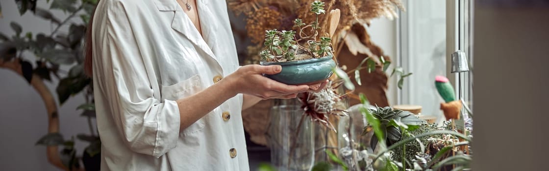 caucasian confident happy florist is working with composition made from glass stones and plants in botanic shop