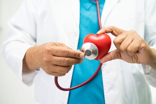 Doctor holding a red heart in hospital ward, healthy strong medical concept.
