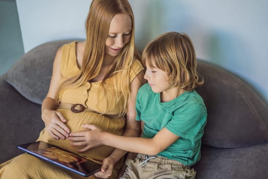 Mom and her son looking on ultrasound image of his unborn baby brother on mothers tablet. Concept of healthcare and family happiness expecting baby.