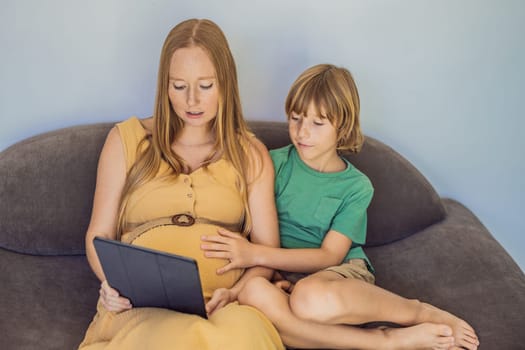 pregnant mom and son look at the tablet. Reading a book or watching a cartoon or making a video call. Look at the photo from the ultrasound.