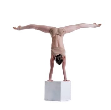 Flexible woman posing doing exercises on cube in studio