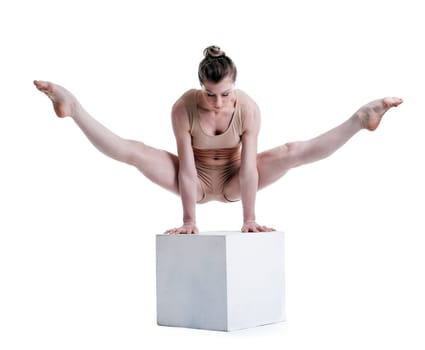 Young pretty acrobat posing with cube in studio, isolated on white