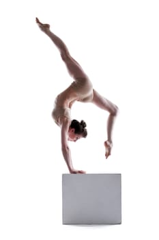 Young flexible woman posing on cube in studio