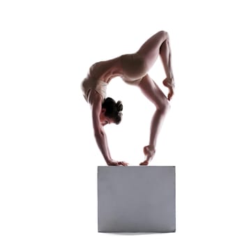 Flexible young woman posing on cube, isolated on white