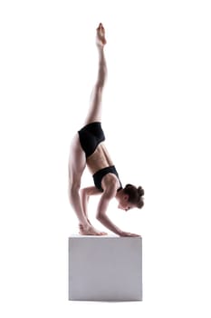 Beautiful girl posing doing exercises on cube, isolated on white