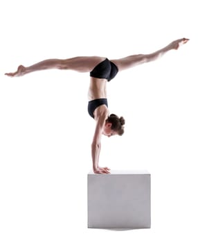 Flexible gymnast balancing on cube in studio, isolated over white background