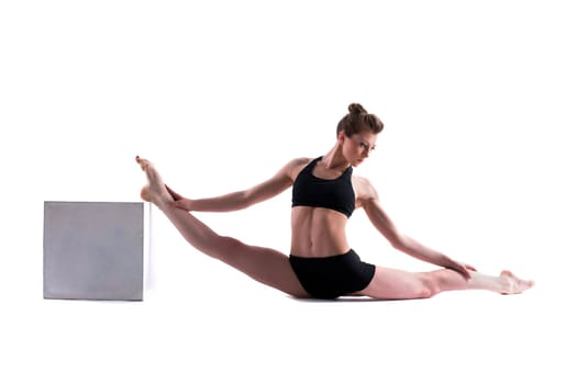 Attractive gymnast posing with cube in studio, isolated on white