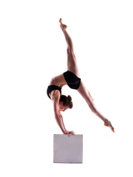 Flexible sporty girl posing on cube in studio, isolated on white
