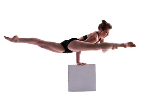 Young pretty brunette doing exercises on cube in studio