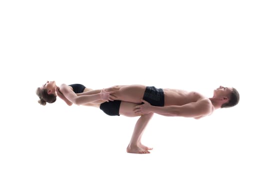 Couple of flexible gymnasts balancing in studio, isolated on white