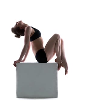 Beautiful woman posing on cube in studio, isolated over white background
