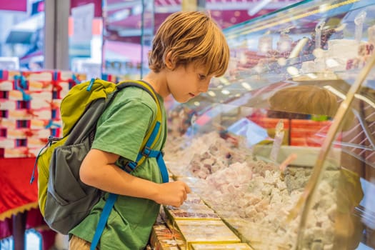 The boy looks at the counter with Turkish sweets. Traditional oriental sweet pastry cookies, nuts, dried fruits, pastilles, marmalade, Turkish desert with sugar, honey and pistachio, in display at a street food market.