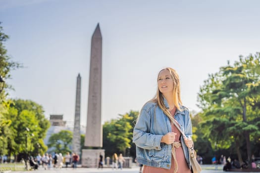Woman Tourist in Istanbul against the background of Obelisk of Theodosius is the Ancient Egyptian obelisk of Pharaoh Thutmose III places in the Hippodrome of Constantinople, Turkey. Theodosius Dikilitasi.