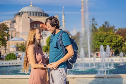 Happy couple of tourists in the honeymoon in Istanbul enjoy beautiful view on Hagia Sophia Cathedral, famous islamic Landmark mosque, Travel to Istanbul, Turkey. Sunny day architecture and Hagia Sophia Museum, in Eminonu, istanbul, Turkey. Turkiye.