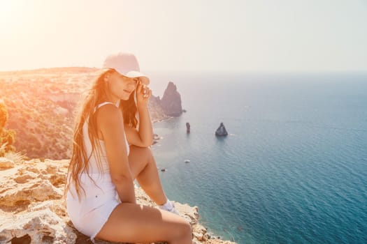 Woman travel sea. Young Happy woman in a long red dress posing on a beach near the sea on background of volcanic rocks, like in Iceland, sharing travel adventure journey