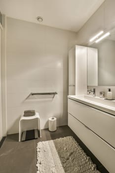 a modern bathroom with white walls and black tile on the floor, there is a large mirror in the corner