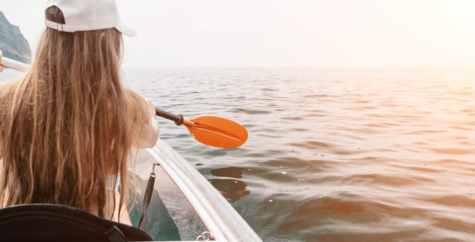 Woman in kayak back view. Happy young woman with long hair floating in transparent kayak on the crystal clear sea. Summer holiday vacation and cheerful female people having fun on the boat.